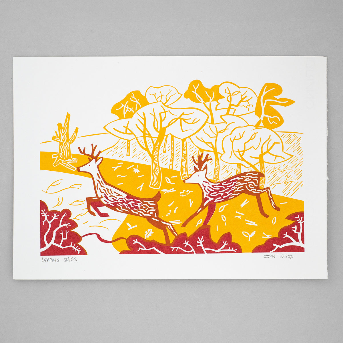 Leaping Stags screenprint in orange and red showing two stags leaping over bushes in front of woods.