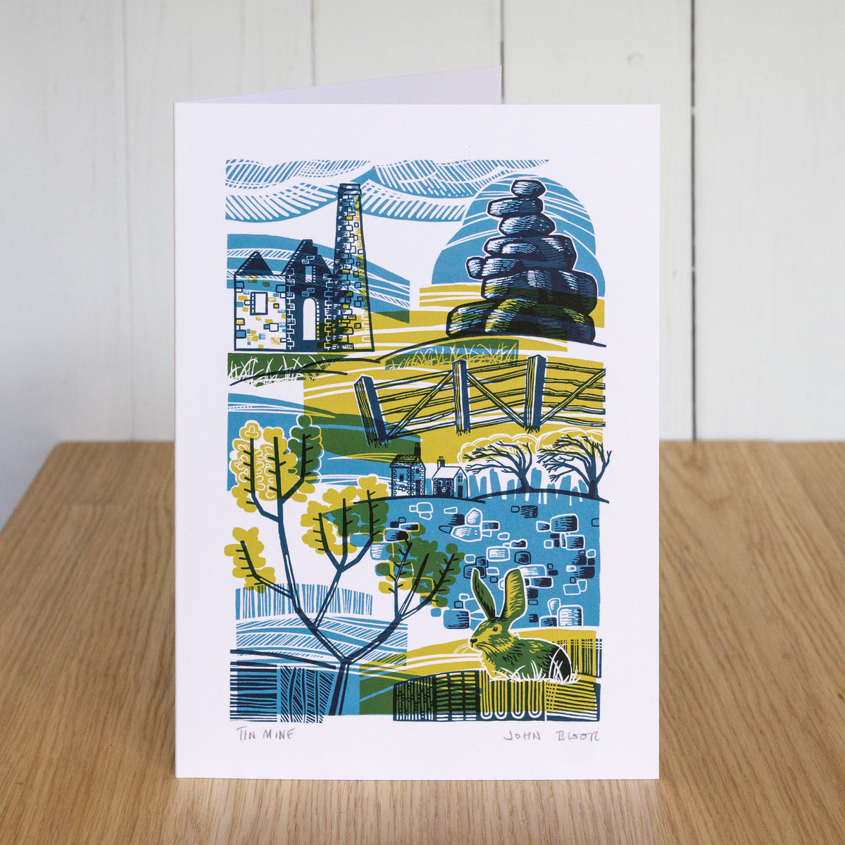 Tin Mine card. It depicts a tin mine, rock stack, gorse, a rabbit, a dry stone wall, fence and houses. It is in an abstract style.