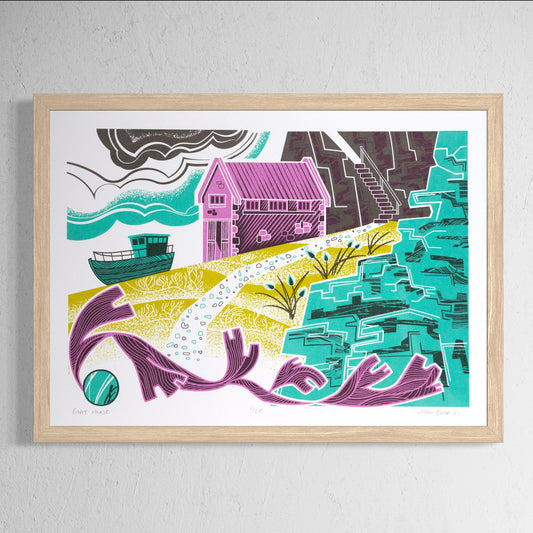 Boat House screenprint. It depicts a pink boat house and green boat on a slipway, with cliffs to the right, sand and seaweed in the foreground. 