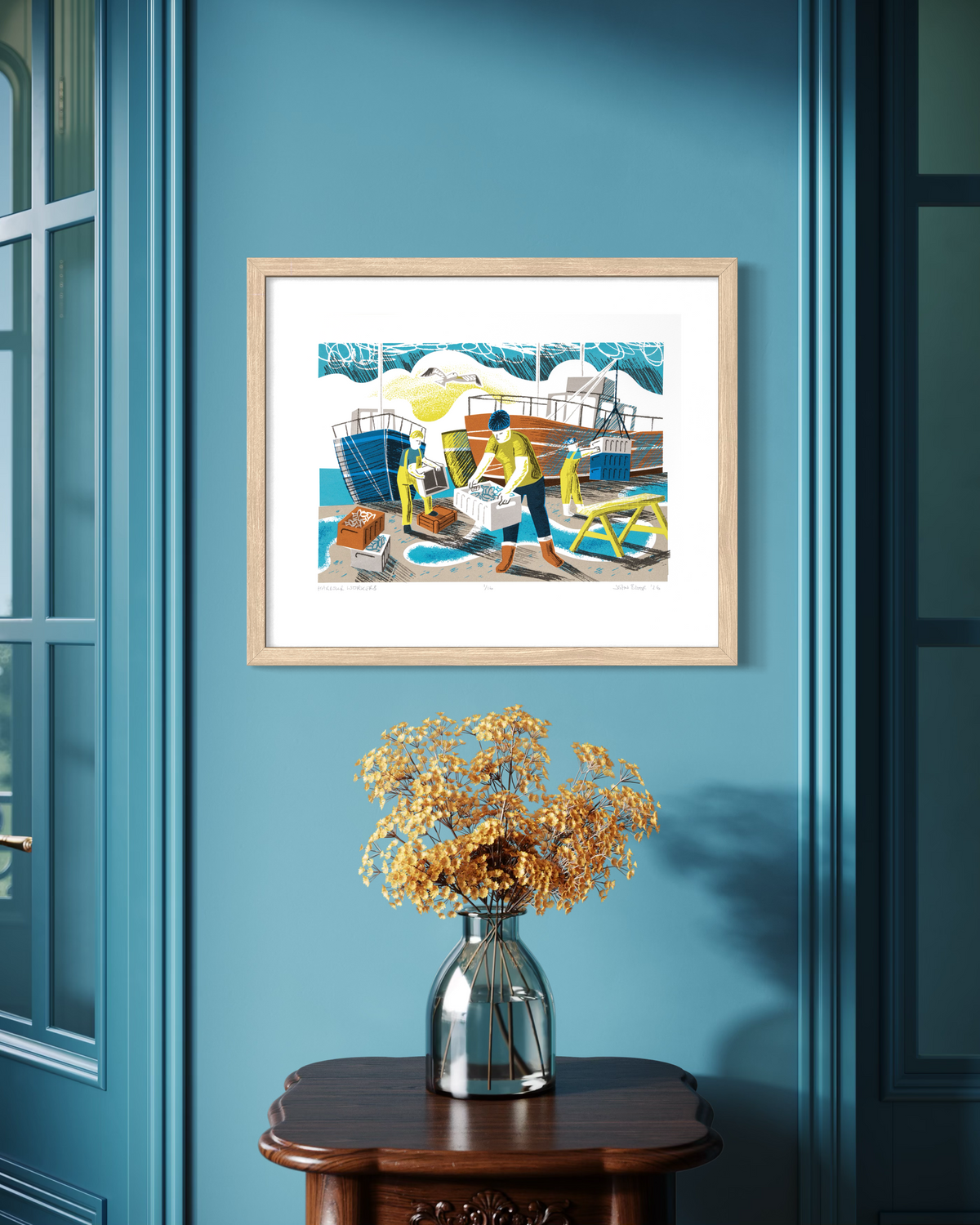 A hand printed screenprint showing harbour workers unloading fish with boats behind. It is part of my working people series of prints which are inspired by traditional occupations in Britain. Shown in an oak frame on a blue wall.
