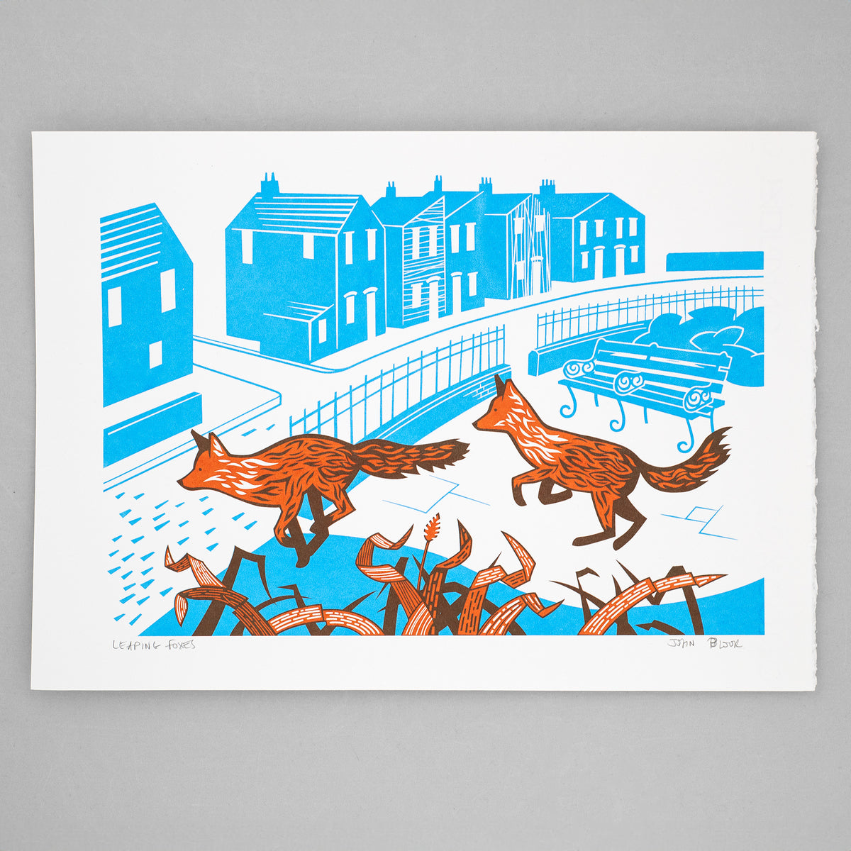 Leaping Foxes screenprint in orange and cyan showing two foxes leaping over grasses in front of an urban street scene.