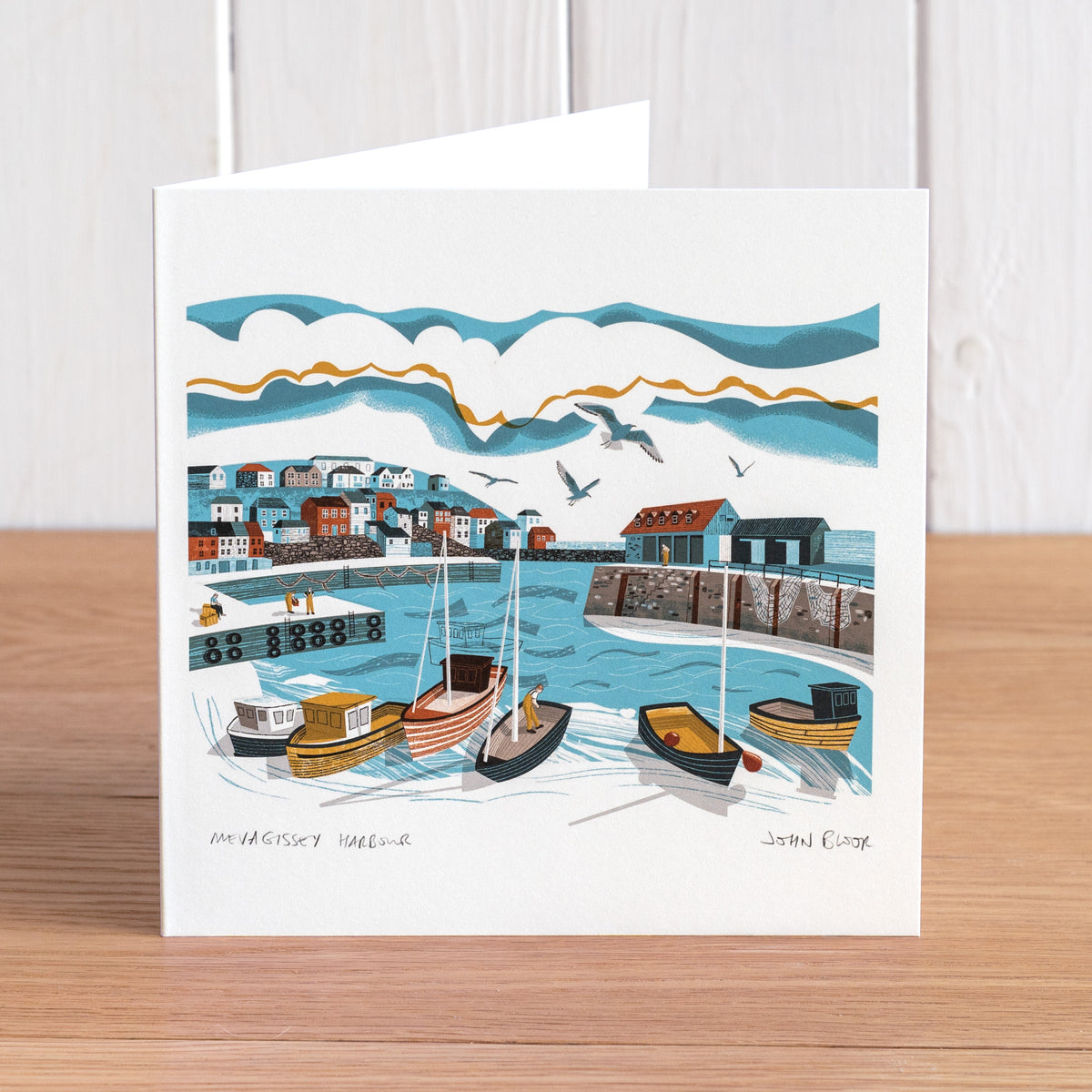 Mevagissey Harbour greetings card. It features a view of Mevagissey Harbour, Cornwall, looking out across the harbour with boats, harbour wall and houses.