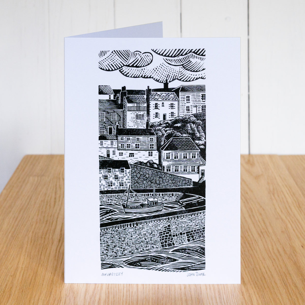 Greetings card which depicts Mevagissey Harbour, the houses over the harbour and the harbour wall. Based on a linocut.
