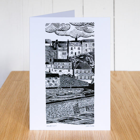 Greetings card which depicts Mevagissey Harbour, the houses over the harbour and the harbour wall. Based on a linocut.