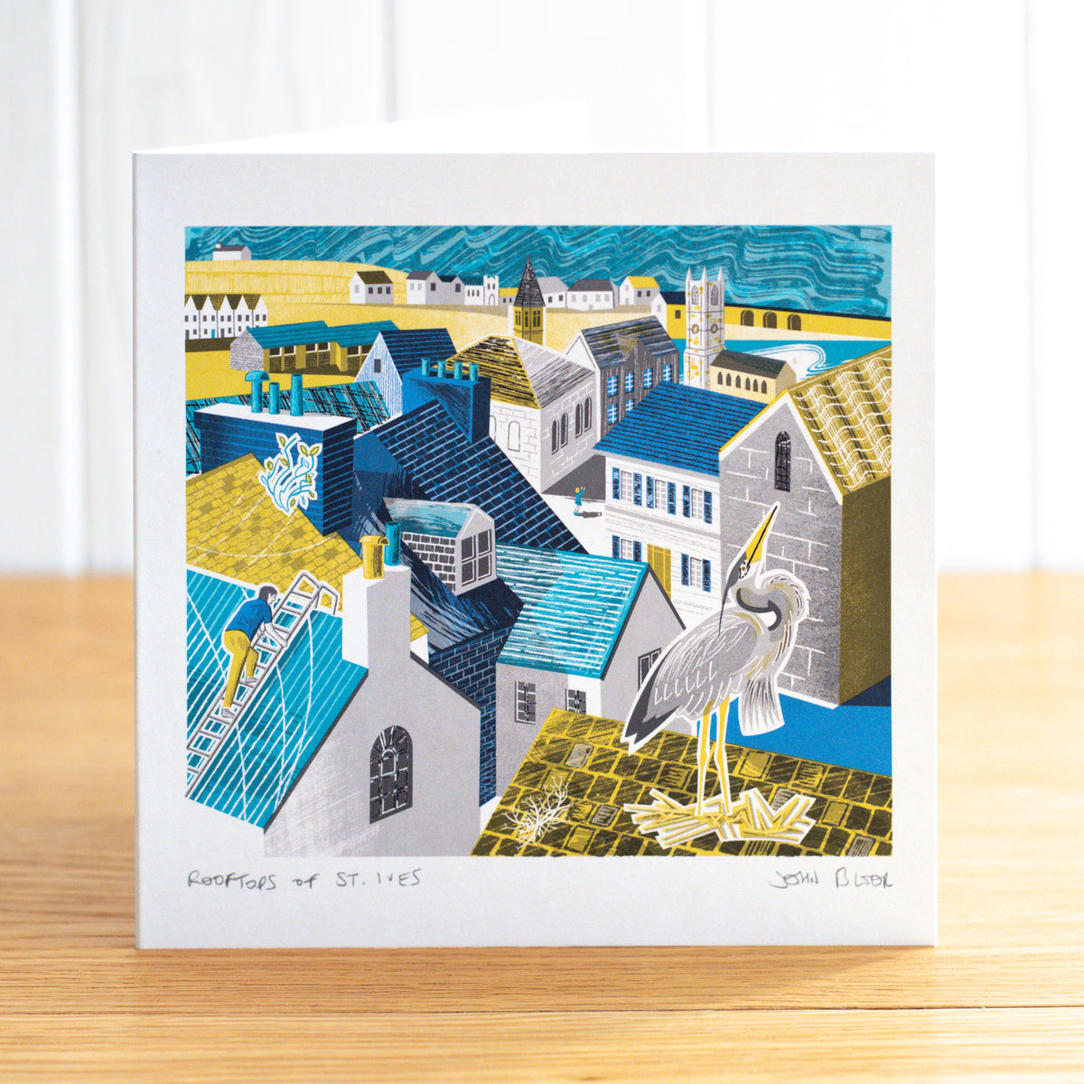 Rooftops of St. Ives greetings card, depicting the view over the rooftops of St. Ives, Cornwal, looking towards the harbour. It is in yellow, blue and turquoise.