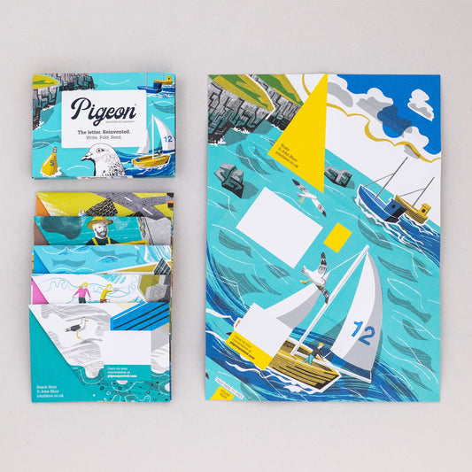 Safe Harbour Pigeons stationery. There are various scenes including boats on the sea, beach huts, cliffs and children playing on rocks, fishermen at a harbour moving fish, a harbour town and a coastal valley.