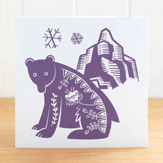 This is a Scandi Forest influenced greetings card featuring a bear, snowflakes and a mountain. It is printed in purple.