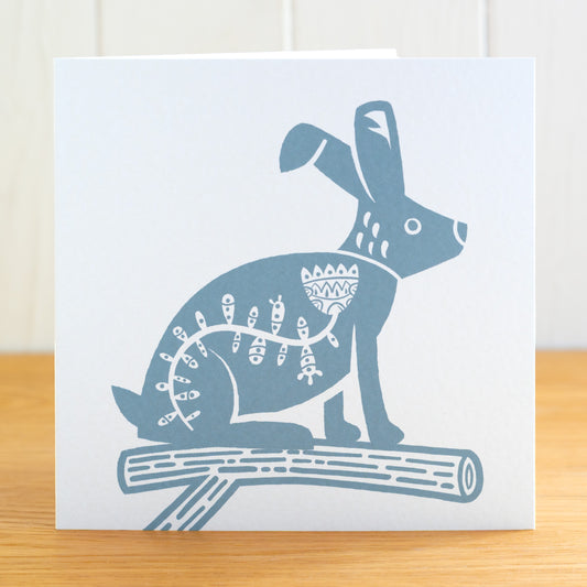 This is a Scandi Forest influenced greetings card featuring a hare on a fir branch. It is printed in icy blue.