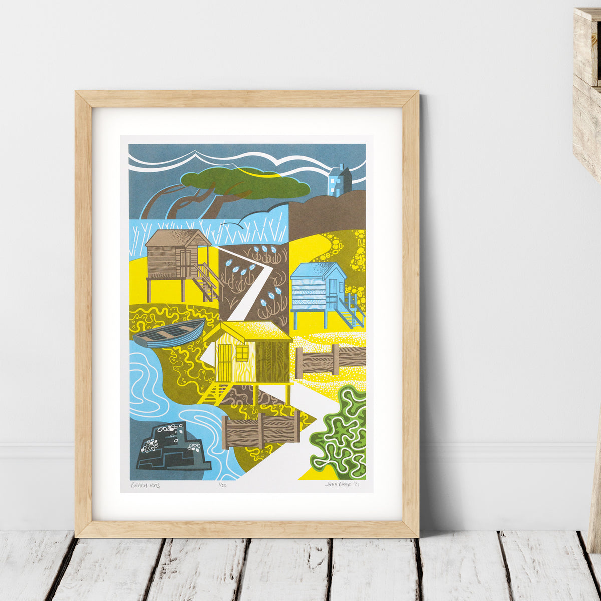 Beach Huts screenprint. The print depicts three beach huts with steps down to the beach, a windswept tree, groynes, sea foam, mussels on a rock and sea kale. 