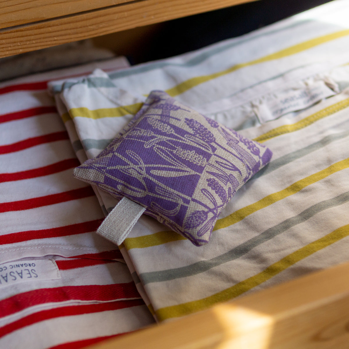 A square lavender bags with hanging loop hand printed with a lavender design.