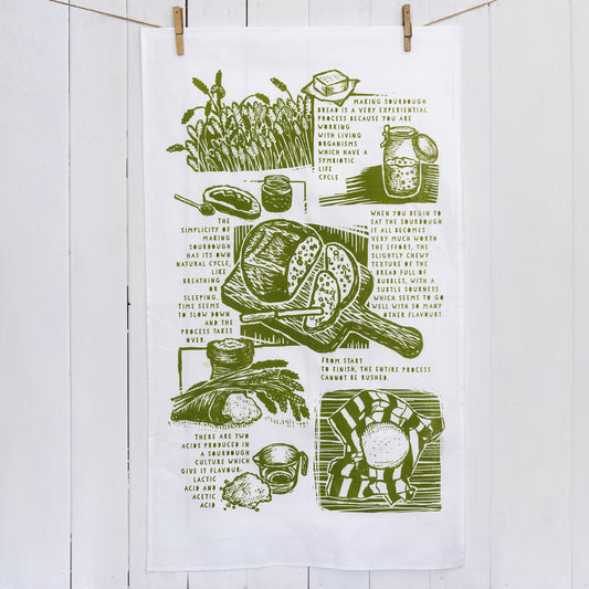 A screen printed tea towel in olive green featuring illustrations and words about the joy of making sourdough bread.