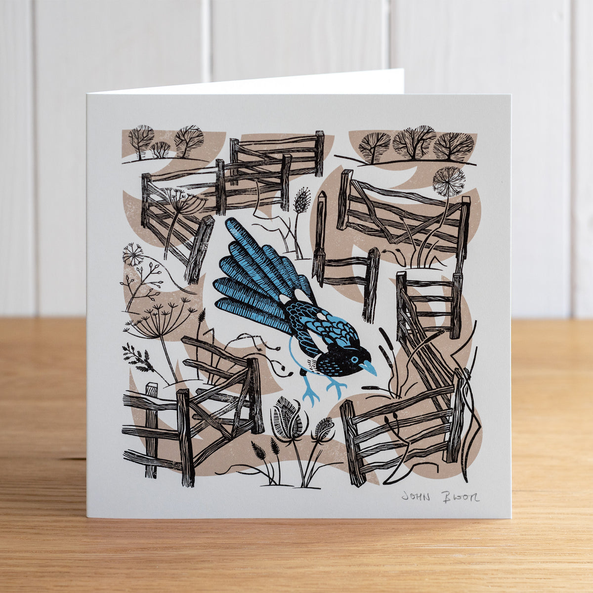 Take Flight Magpie greetings card. This card depicts a Magpie standing amongst fences and seed heads. 