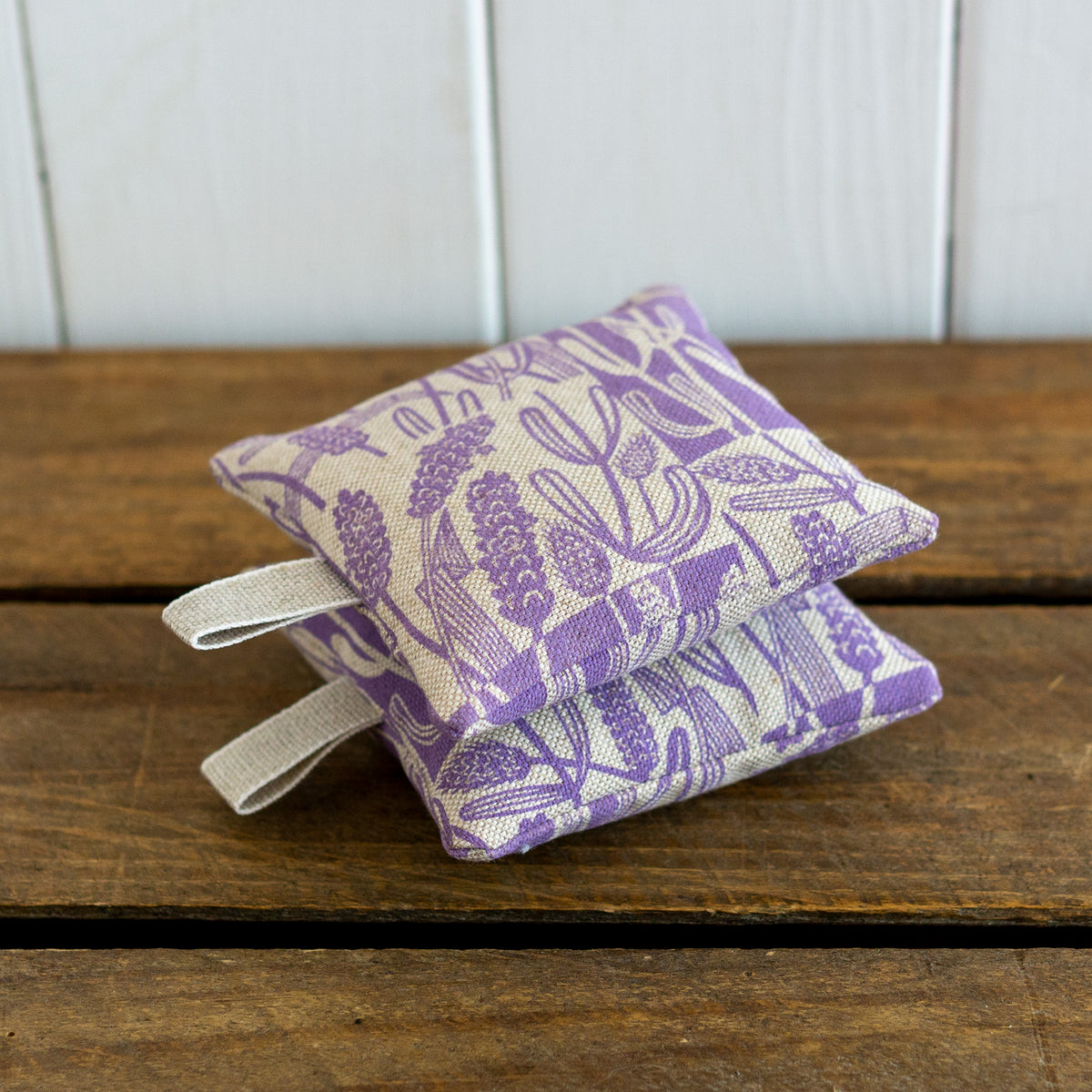 Two square lavender bags with hanging loops hand printed with a lavender design.