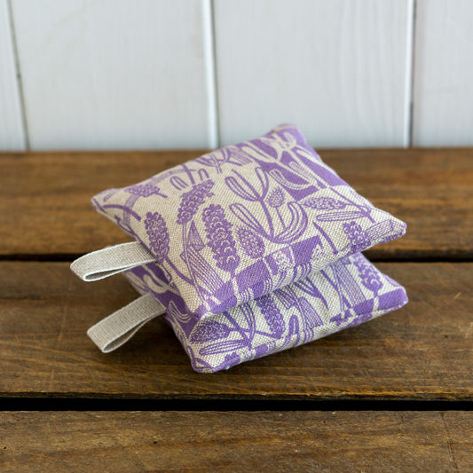Two square lavender bags with hanging loops hand printed with a lavender design.